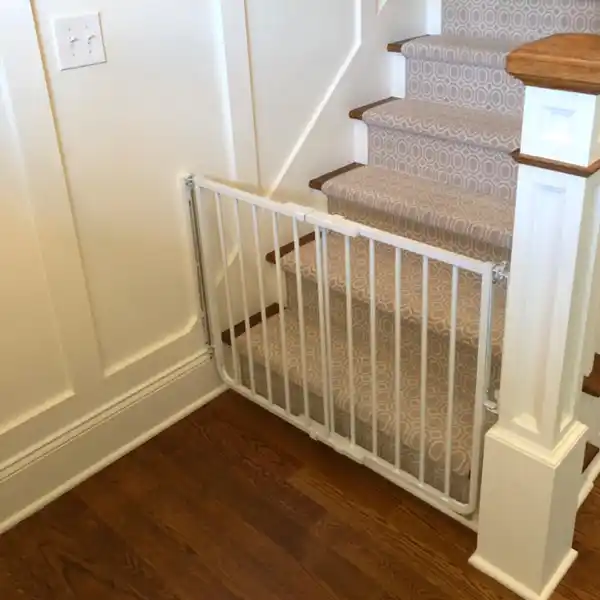 The Cardinal Gates Stairway Special Safety Gate installed at the bottom of a staircase, providing a secure barrier to prevent access. This childproof gate is ideal for ensuring staircase safety and keeping your little explorer safe in high-risk areas of your home.