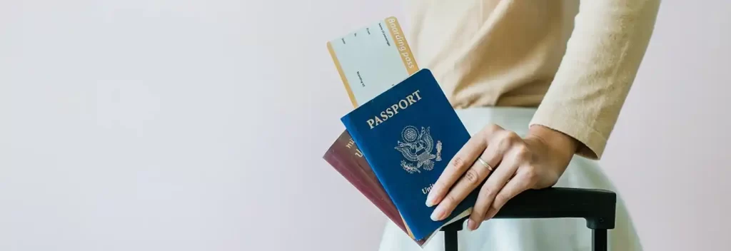 A woman holding her passport and boarding pass, showcasing her travel essentials as she heads to the airport.