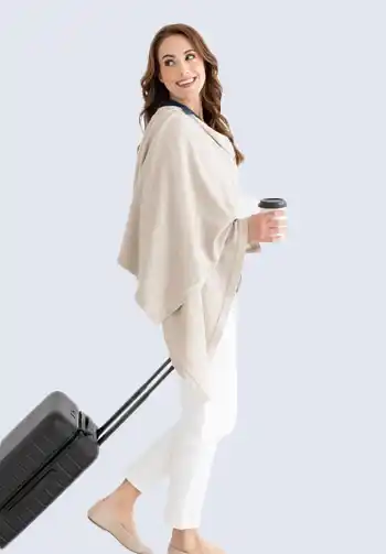 An ultra-soft and stylish beige scarf made of plush organic cotton, a travel essential that can be used as a shawl or blanket to ensure comfort on your journey.