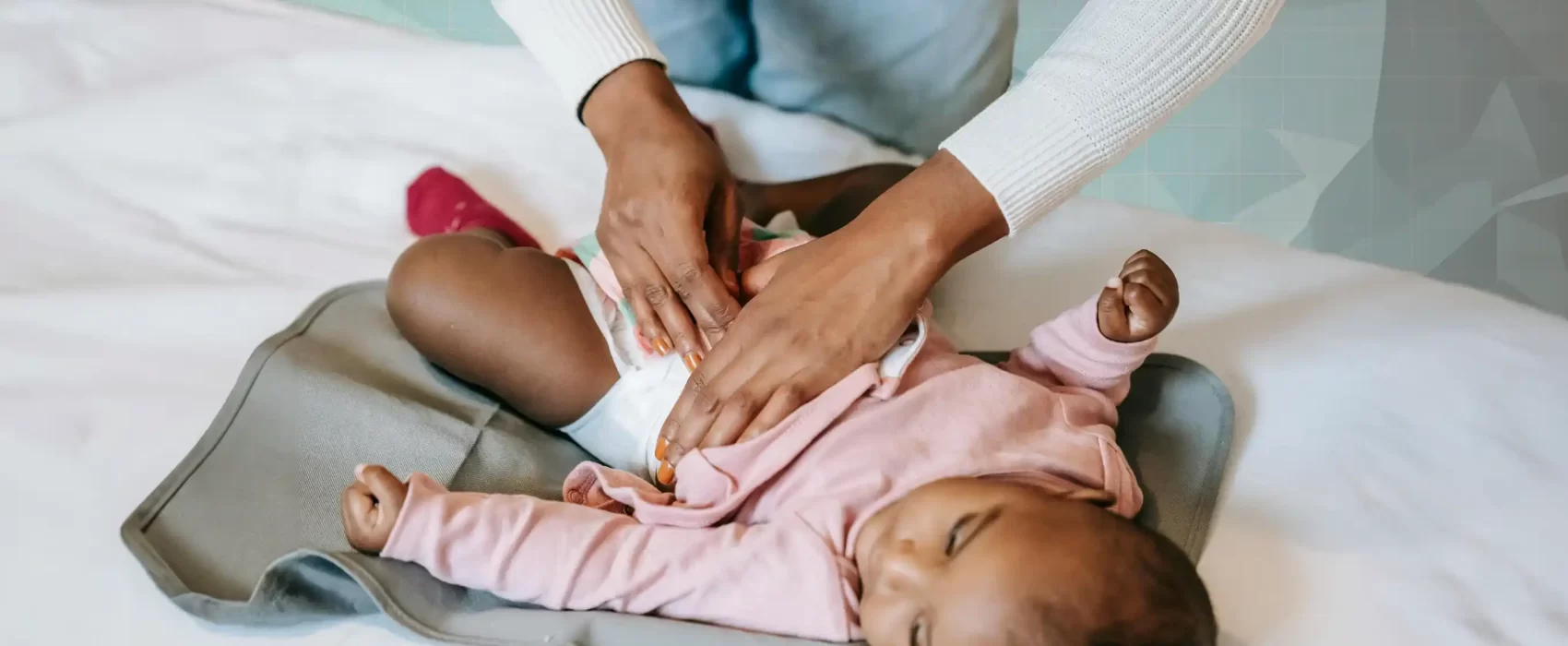 A parent changing a baby's diaper on a portable changing pad, illustrating the importance of having essential diapering supplies in your diaper bag.