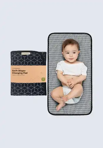 A portable changing pad with a geometric pattern, featuring a baby lying on it, ideal for convenient and hygienic diaper changes, great for your diaper bag.