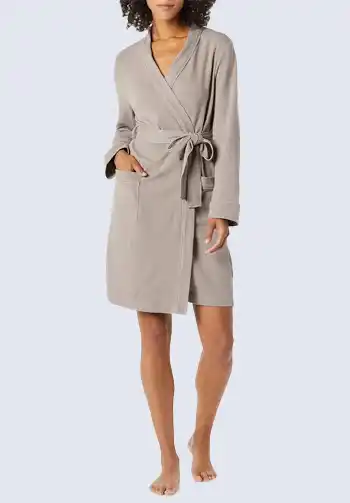 A woman wearing a lightweight, beige robe with a tie waist and pockets, suitable for hospital stays, breastfeeding, and essential for a hospital bag list for birth.