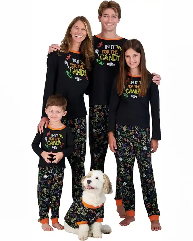 Matching family Halloween pajamas featuring black tops with 'In It for the Candy' text and colorful candy graphics, paired with festive pants adorned with Halloween motifs, perfect for a fun and sweet Halloween celebration.