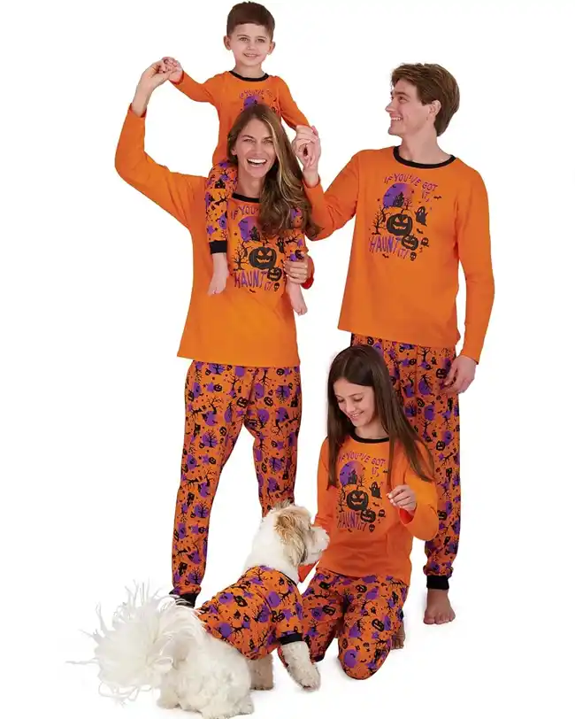 Matching family Halloween pajamas with bright orange tops featuring a playful pumpkin graphic and the phrase 'If You've Got It, Haunt It,' paired with orange pants adorned with Halloween motifs, perfect for a festive and fun Halloween celebration.