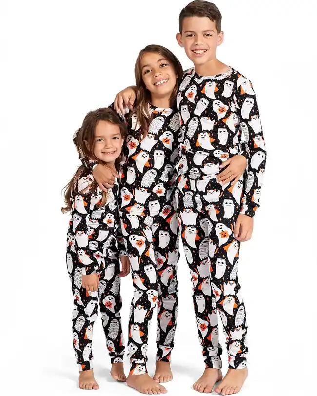 Three children wearing matching family Halloween pajamas with playful ghost patterns, perfect for a festive and fun Halloween celebration.