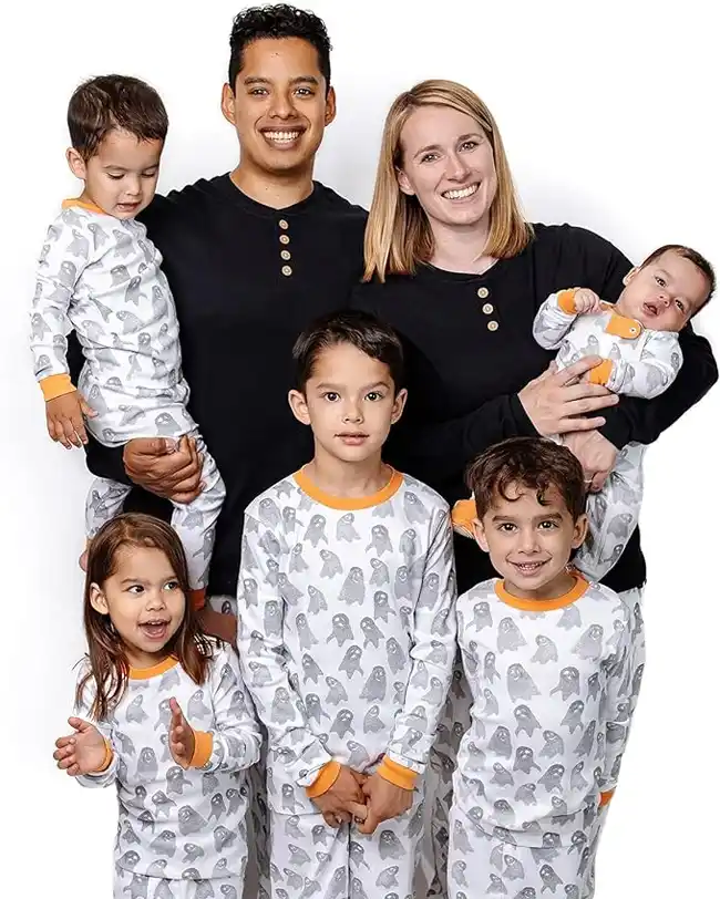 A family wearing matching Halloween pajamas with gray ghost patterns and orange cuffs, perfect for a cozy and festive Halloween celebration.