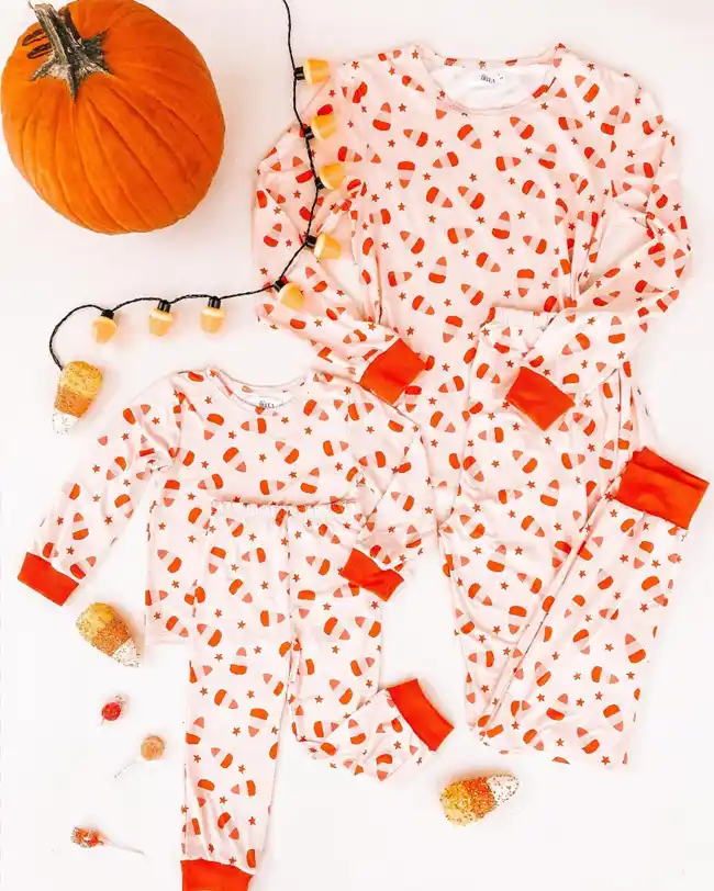 Matching family Halloween pajamas featuring a candy corn pattern on a white background with orange cuffs, perfect for adding a touch of sugary fun to your Halloween celebrations.