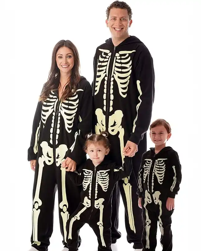 Matching family Halloween pajamas featuring glow-in-the-dark skeleton designs on black onesies, perfect for adding spooky fun to your Halloween night.