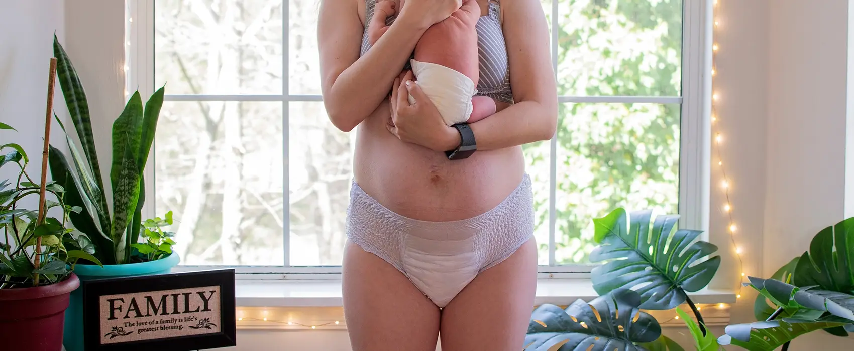 New mom holding baby, wearing postpartum underwear for comfort and support.