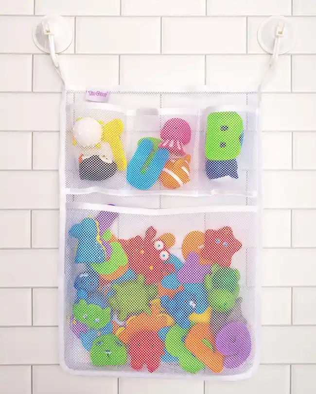 A mesh bath toy organizer with multiple pockets attached to a tiled bathroom wall, filled with various bath toys, providing an organized and hygienic storage solution.