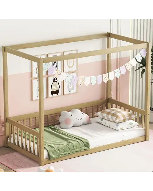 A charming Montessori floor bed featuring a wooden canopy frame and protective guardrails. The toddler floor bed has a low profile to encourage independence, and it is decorated with a pastel bunting banner. The cozy setup includes soft pillows and a green blanket, creating a warm and inviting sleep environment. The room is adorned with playful wall art, making it perfect for fostering a sense of ownership and comfort for young children.