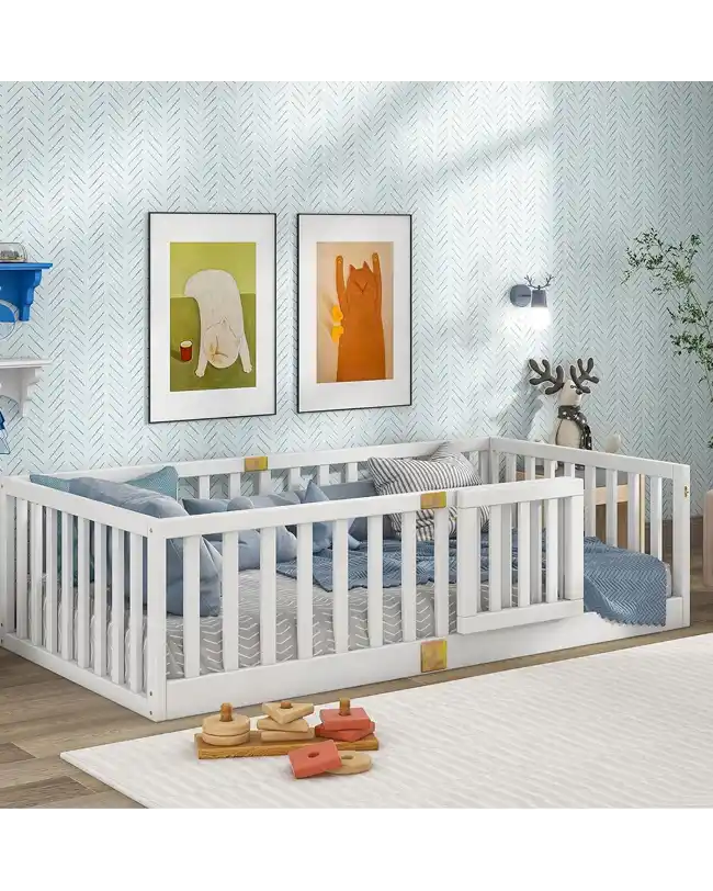 A Montessori floor bed featuring sturdy guardrails, designed to provide a safe and secure sleep environment for toddlers. The bed has a low profile, allowing children to climb in and out independently, promoting self-reliance. The white wooden frame is complemented by soft blue and grey bedding, creating a cozy and inviting sleep space. The room is decorated with playful wall art and modern decor, making it a perfect addition to any child's bedroom.