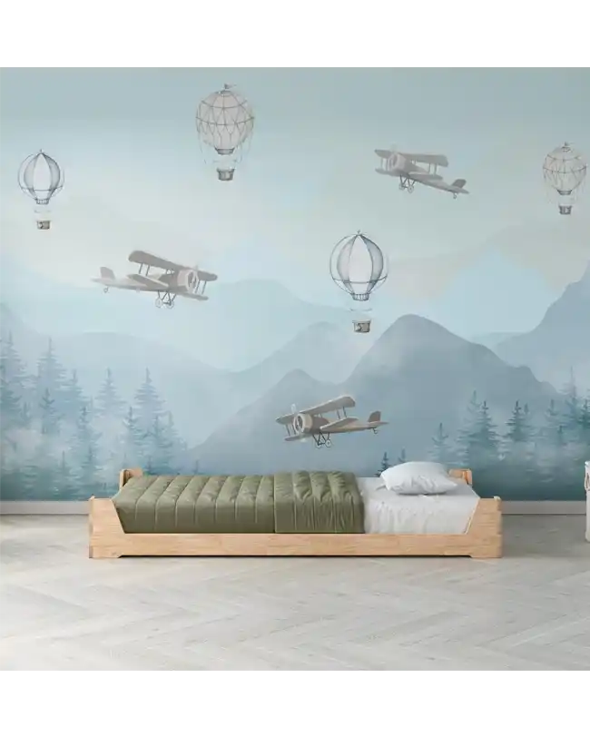 A minimalist Montessori floor bed with a natural wood frame, placed against a beautiful scenic mural featuring hot air balloons and vintage airplanes. The toddler floor bed has a low profile, making it easy for young children to climb in and out independently. The simple design and green bedding create a peaceful and inviting sleep environment, perfect for encouraging imagination and a sense of adventure.