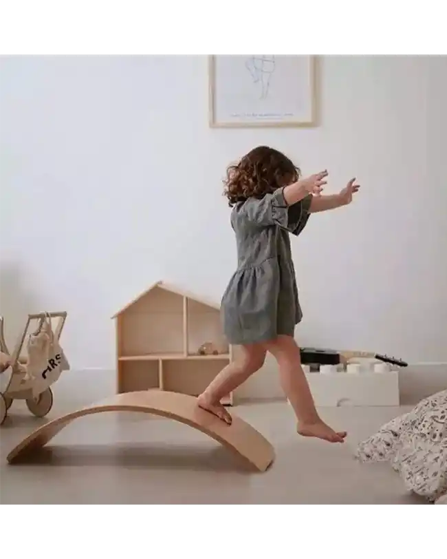 A young child balancing on a wooden balance board, promoting coordination and strength, ideal for Montessori toys for 1 year olds.