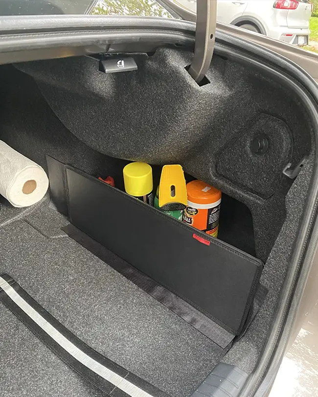 A trunk sidewall divider storing car cleaning supplies and paper towels, optimizing space and keeping items organized in the car trunk.