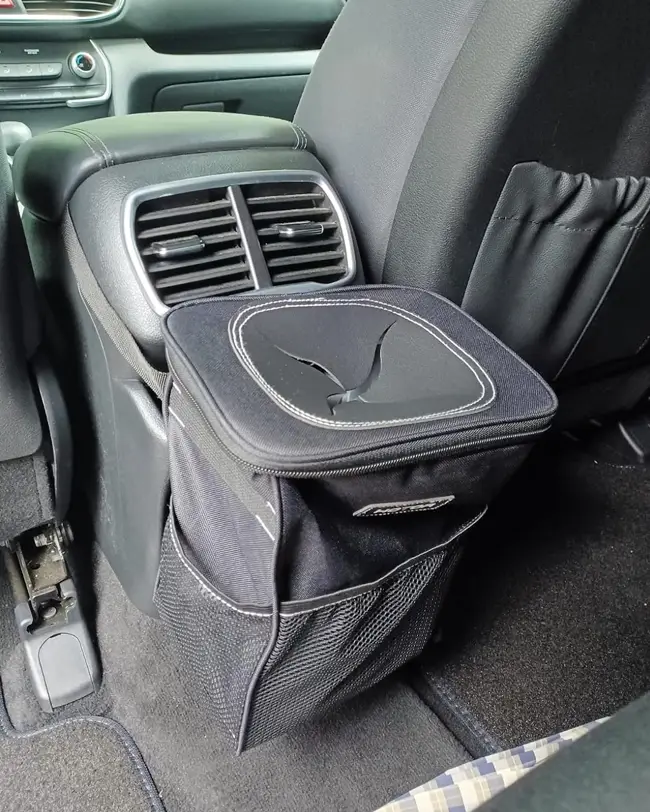 A car trash can with a lid placed behind the car seat, helping keep the backseat clean and enhancing car organization.