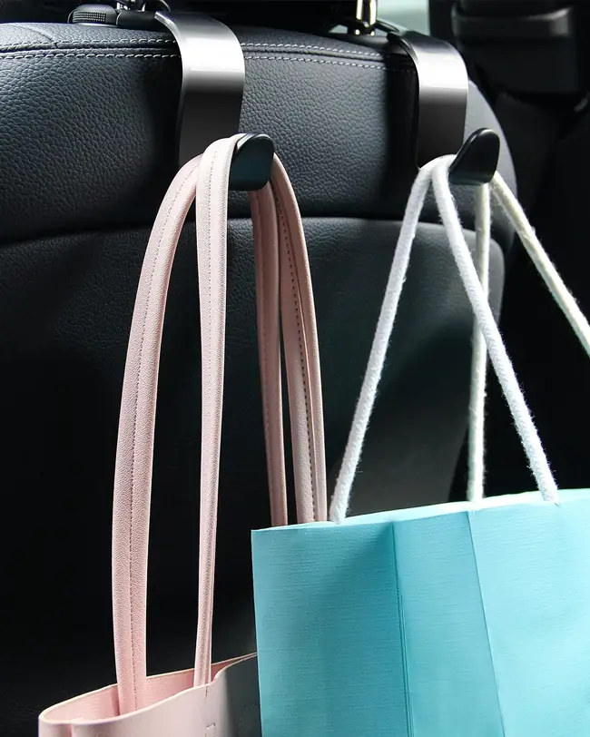 Headrest hooks holding bags in the backseat of a car, perfect for optimizing car organization and keeping items off the floor.