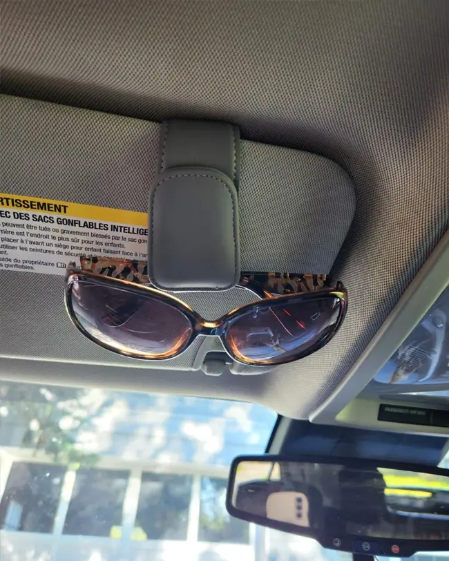 A magnetic sunglass holder attached to a car visor, keeping sunglasses secure and improving front seat car organization.