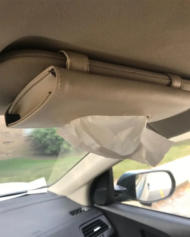 A tissue holder attached to the car visor, providing easy access to tissues and enhancing front seat car organization.