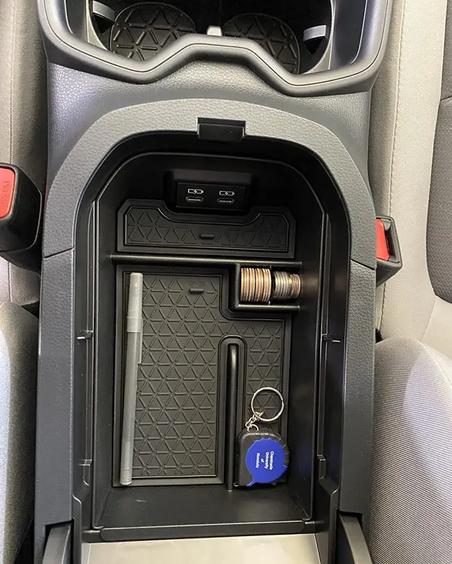 A car console organizer featuring a designated coin storage area, keeping small items like pens and keys neatly organized for improved car organization.