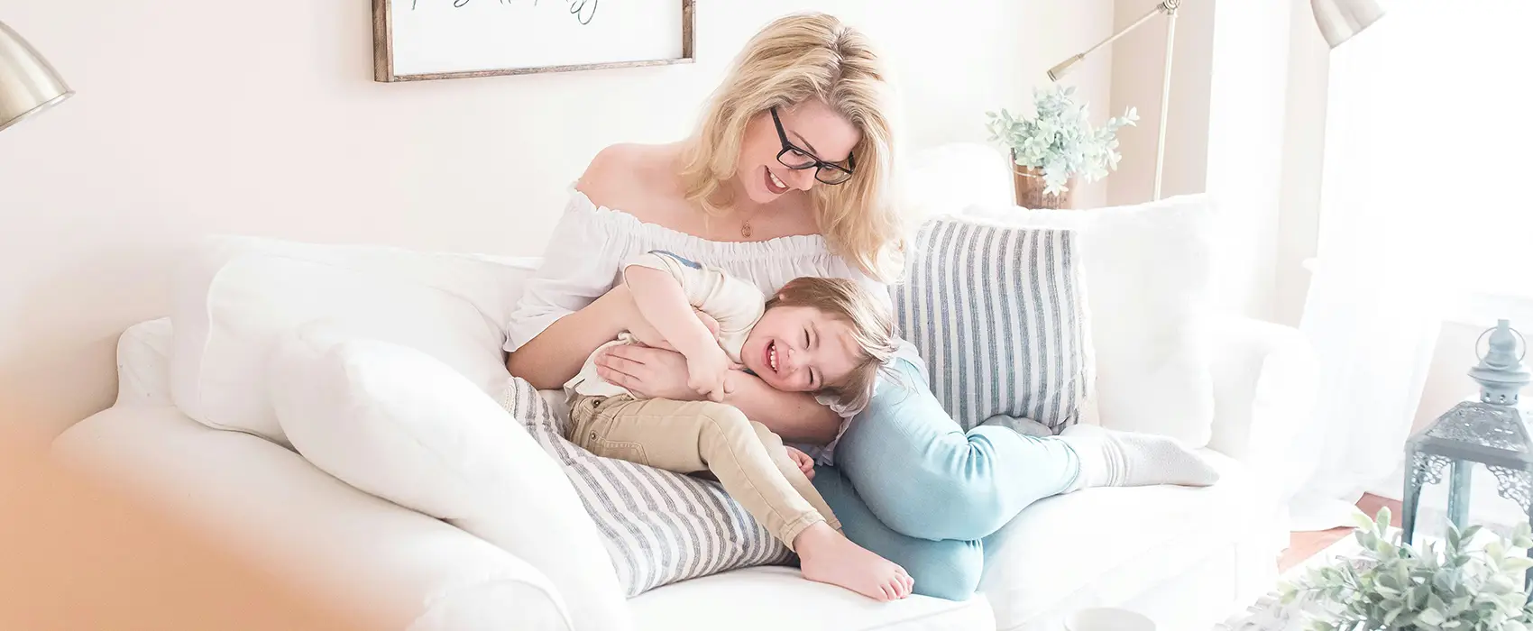 A stay-at-home mom enjoys a cozy moment with her child on the couch, reflecting the joy and balance that come from adopting daily stay-at-home mom habits.