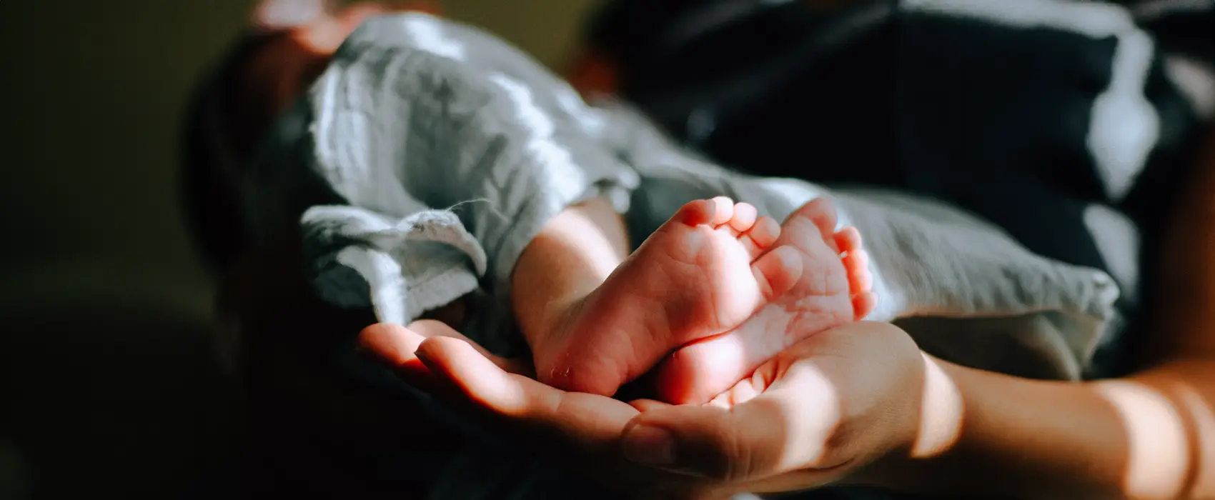 A tender image of a baby’s tiny feet resting in a parent’s hand, symbolizing love and care, perfect for inspiring heartfelt baby quotes.