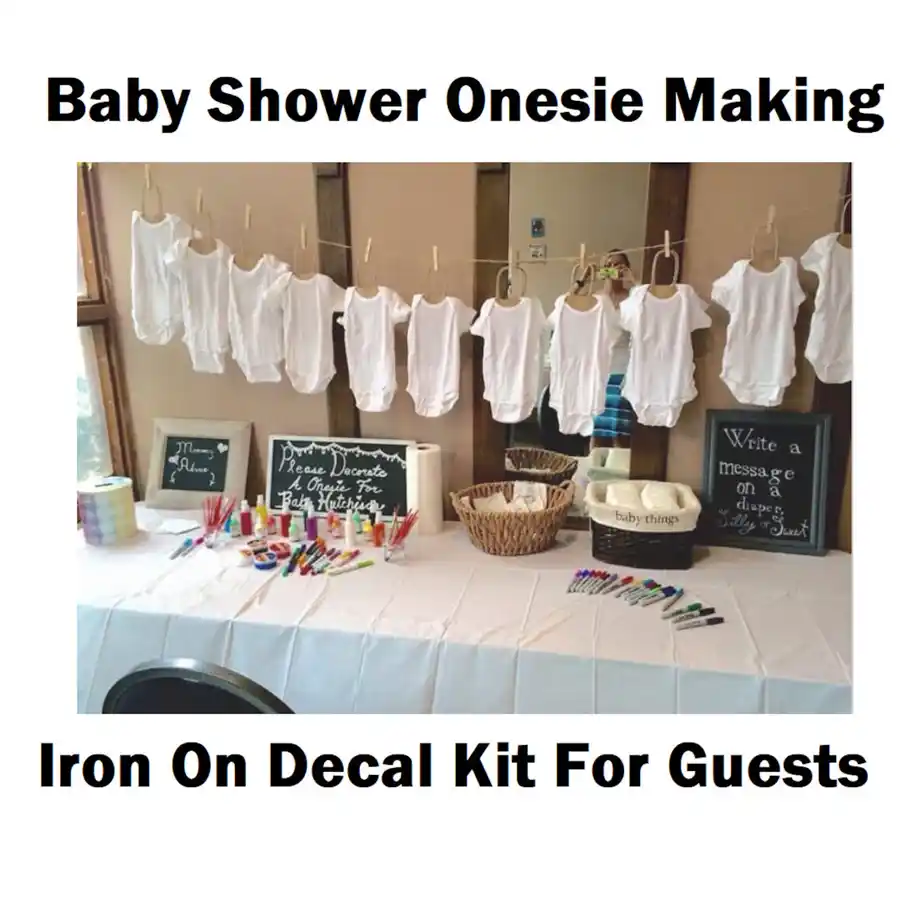 A full setup for a baby shower onesie decorating activity, complete with markers, decals, and clothesline display.