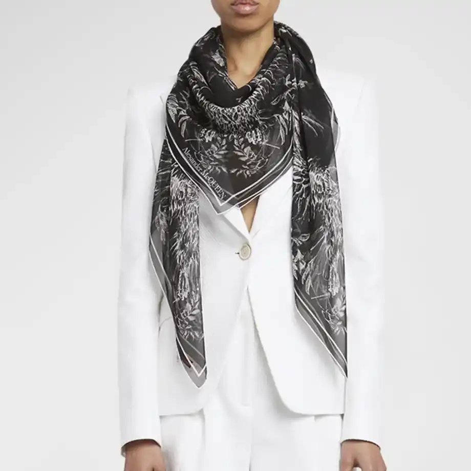 A black silk scarf with intricate patterns worn over a white blazer, an elegant 12-Year Anniversary Gift.