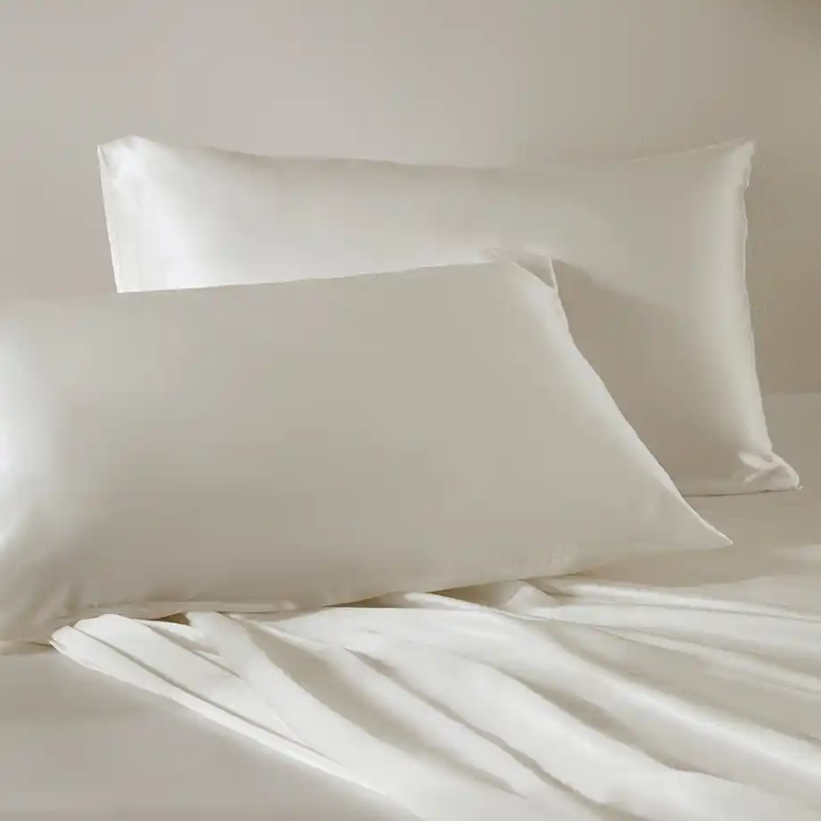 Luxurious white silk pillowcases arranged on a bed, an elegant 12-Year Anniversary Gift.