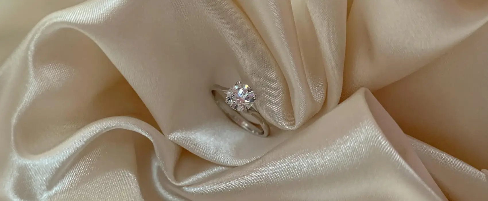 Close-up of a stunning diamond ring resting on luxurious cream silk fabric, symbolizing timeless love and perfect for 12-Year Anniversary Gifts.