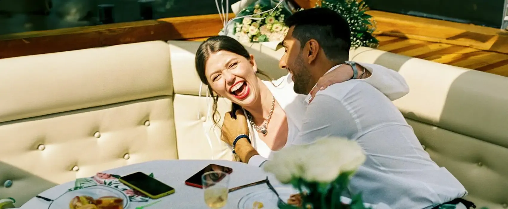 A joyful couple laughing and embracing at an outdoor restaurant, celebrating their anniversary, perfect for inspiration on anniversary quotes for a wife.