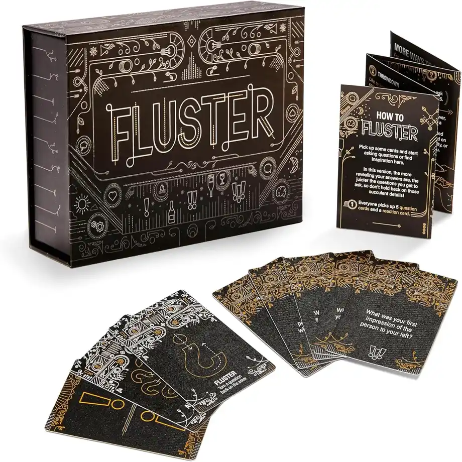 A box of Fluster card game featuring stylish black and gold design, with cards laid out displaying fun and engaging ice breaker questions for social events and parties.