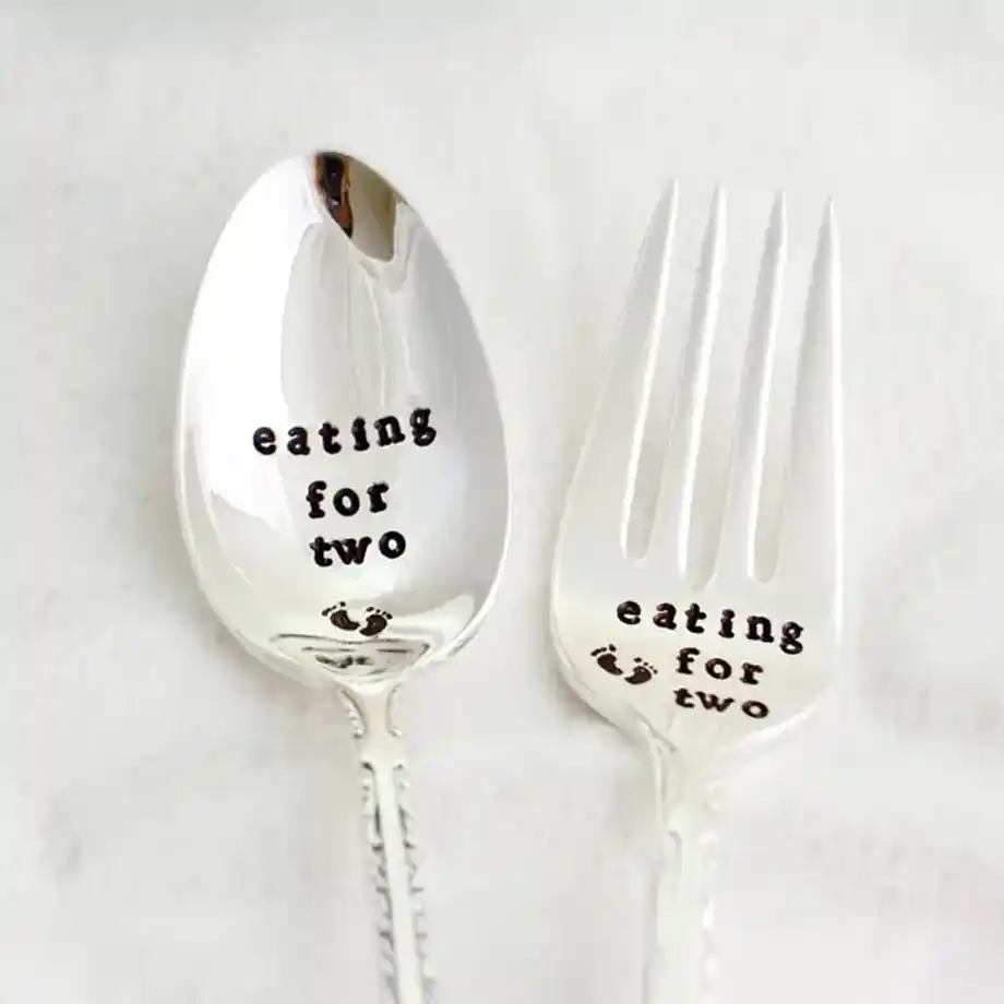 A hand-stamped fork and teaspoon set with the phrase 'Eating for Two,' offering a delightful and creative way to share your pregnancy news, perfect for memorable pregnancy announcement ideas.