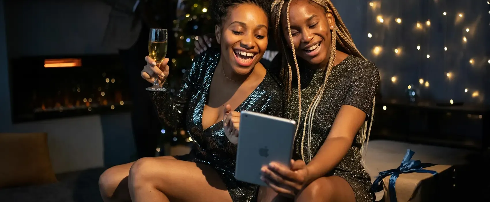 Two women enjoying a virtual baby shower game, one holding an iPad, adding fun and excitement to the online celebration.