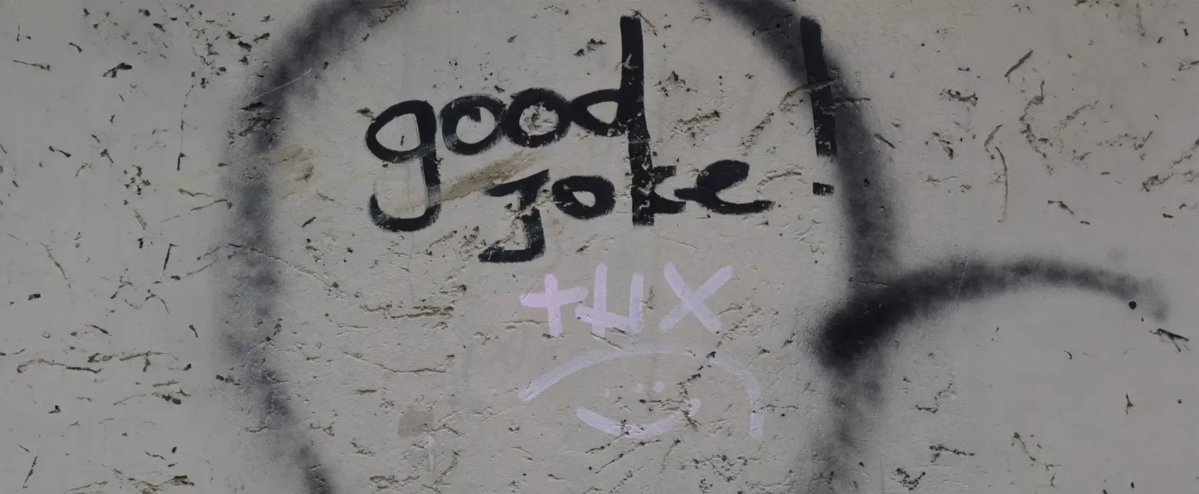 A graffiti wall featuring the text 'good joke!' written in black, with 'THX' and a smiley face in pink underneath. The artwork reflects a playful and edgy vibe, fitting for dark humor jokes.