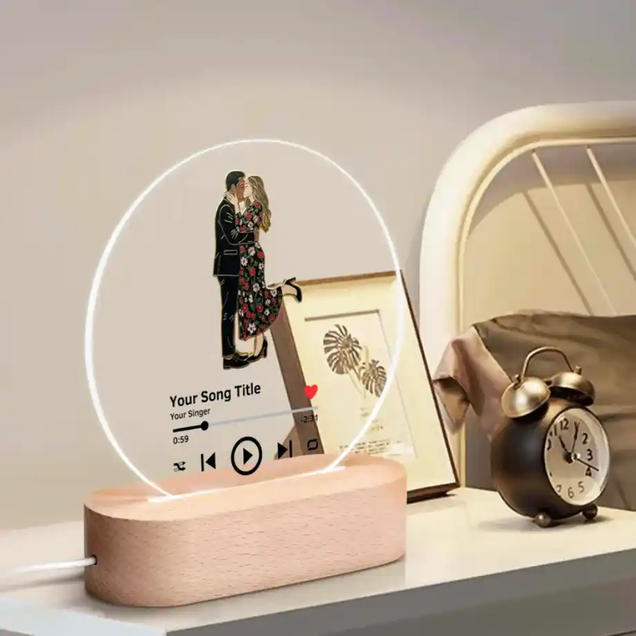 Good morning message for her: A personalized LED night lamp with a music player interface, featuring an illustration of a couple dancing, placed on a wooden base near a vintage alarm clock.