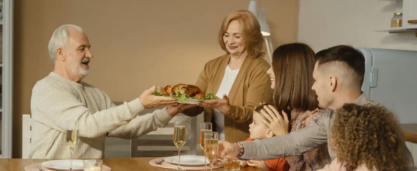 A warm Thanksgiving dinner scene where a family is gathered around the table, sharing a roasted turkey. The table is set with glasses of champagne and festive decor, symbolizing togetherness and gratitude, perfect for happy thanksgiving messages