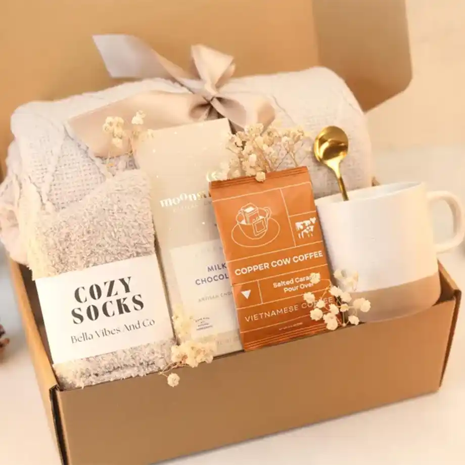 A thoughtfully curated gift basket featuring soft blankets, candles, hot cocoa, and other cozy essentials. Perfect for staying warm and relaxed during chilly days.