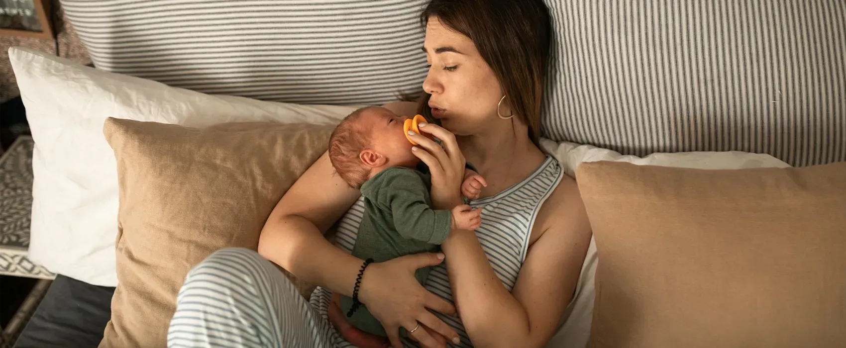 A mother holding her baby close while soothing them during the witching hour, a common fussy period for infants in the evening.