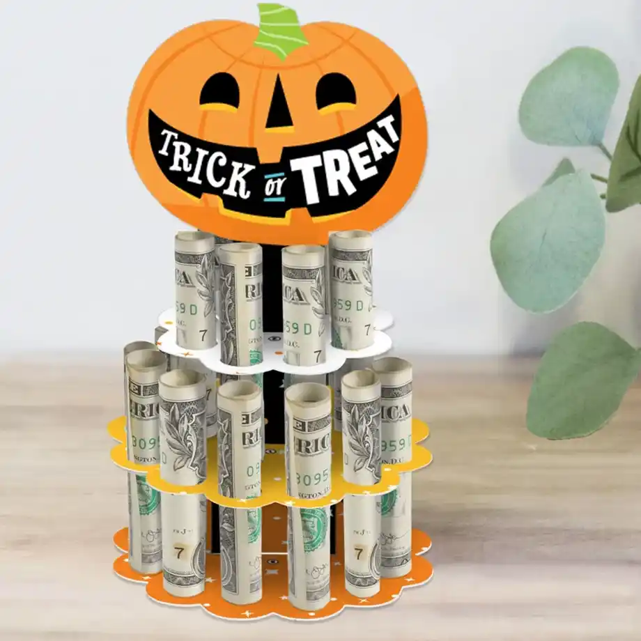 A festive Halloween-themed money tower with rolled dollar bills and a smiling pumpkin topper that says "Trick or Treat," making a unique and fun addition to any Halloween boo basket.