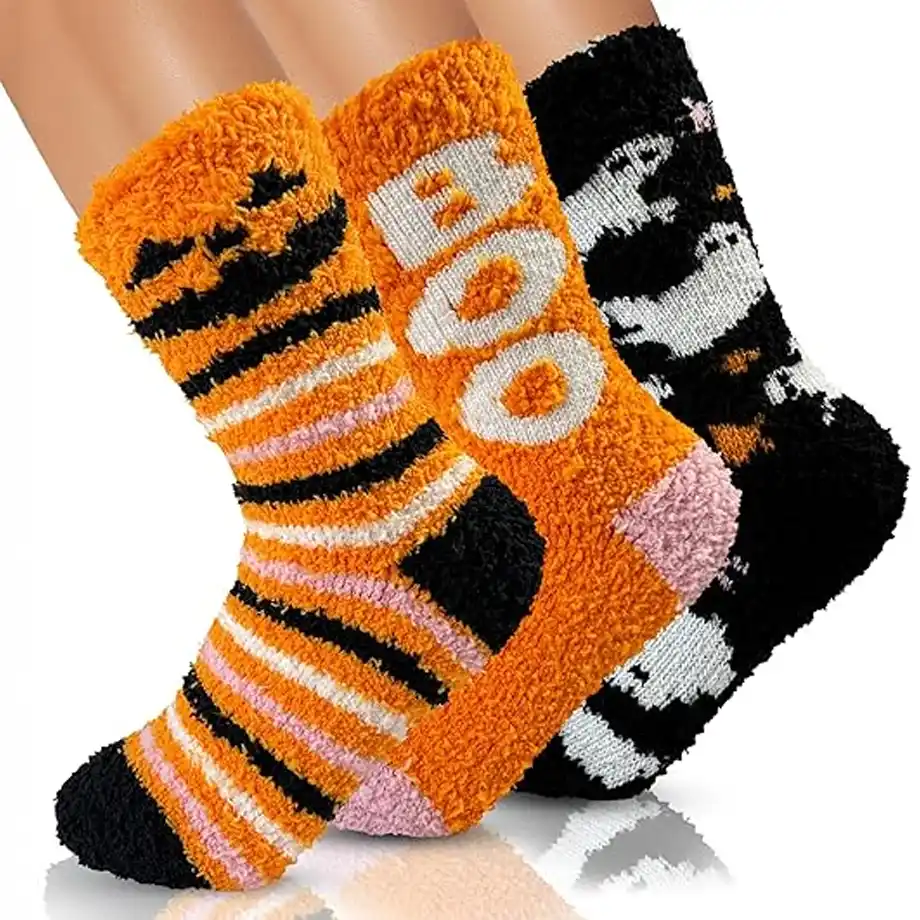 A pair of Halloween-themed fuzzy socks featuring playful jack-o'-lanterns, stripes, and the word "BOO" in bold letters, alongside spooky ghosts — a cozy and festive addition to any Halloween boo basket for a warm and whimsical touch.