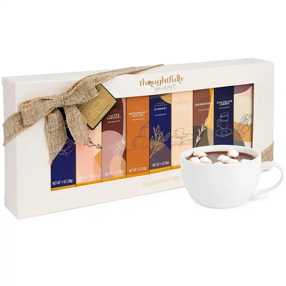 A beautifully packaged Thoughtfully Gourmet hot cocoa gift set featuring six unique flavors, including salted caramel, peppermint mocha, caramel, toasted marshmallow, snickerdoodle, and chocolate cherry. The set is wrapped with a rustic burlap bow, making it an elegant and festive choice for holiday exchanges and white elephant gift ideas. A cozy cup of hot cocoa topped with marshmallows sits beside the gift box, enhancing the warm and inviting feel of the set.