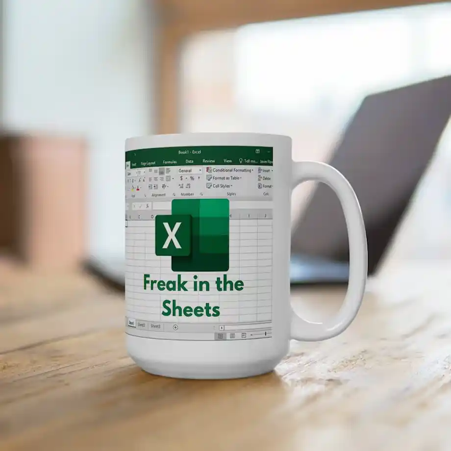 A white ceramic coffee mug featuring a playful Microsoft Excel-themed design with the text "Freak in the Sheets," making it a perfect choice for white elephant gift ideas. This humorous and nerdy gift is ideal for office workers, spreadsheet enthusiasts, and anyone who loves a good pun.