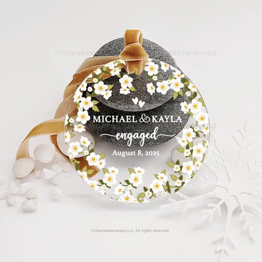 A custom engagement ornament featuring floral accents, personalized with the names "Michael & Kayla," the word "engaged," and the date "August 8, 2025." Decorated with a velvet ribbon, this elegant keepsake makes for a sentimental and stylish choice for engagement gift ideas.