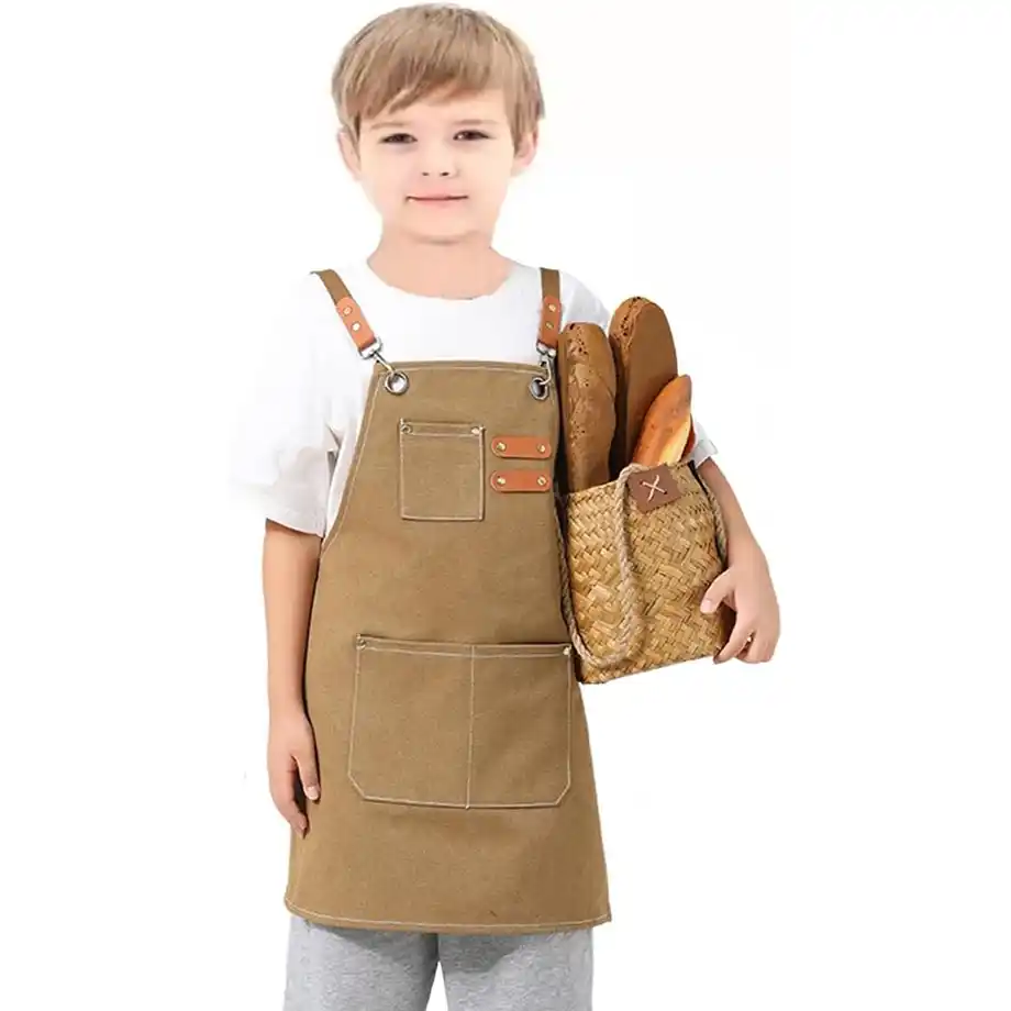 A young boy wearing a brown chef apron with leather straps, holding a woven basket filled with bread. Ideal for pretend play and Indoor Games, this outfit enhances creative role-playing activities for kids. A great choice for engaging and educational Indoor Games!