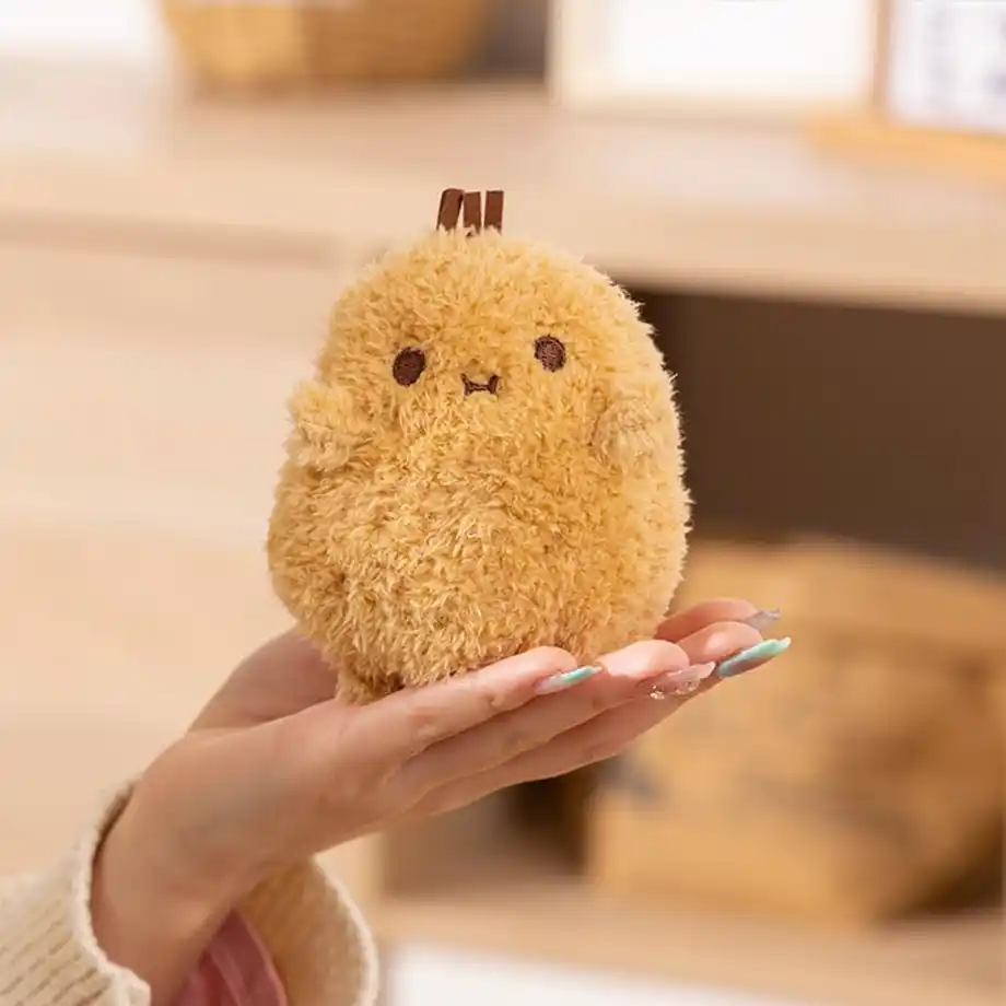 A small, round, fluffy plush toy resembling a chick, held in a person’s hand. This adorable soft toy is perfect for Indoor Games, including storytelling, role-playing, and creative play sessions for kids and families.