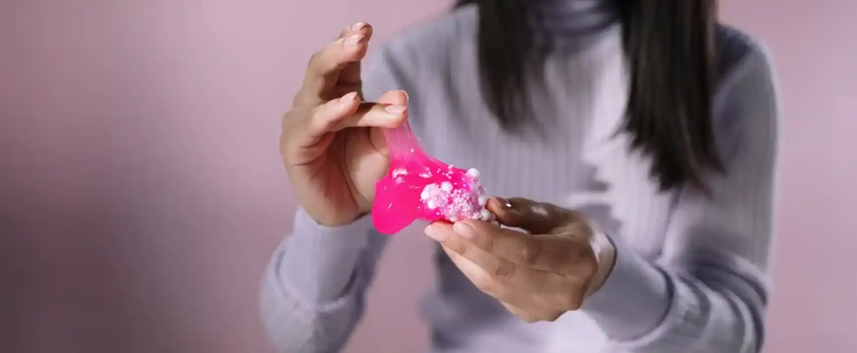 Close-up of a person stretching pink slime with foam beads, illustrating a common mess parents deal with when learning how to get slime out of clothes.